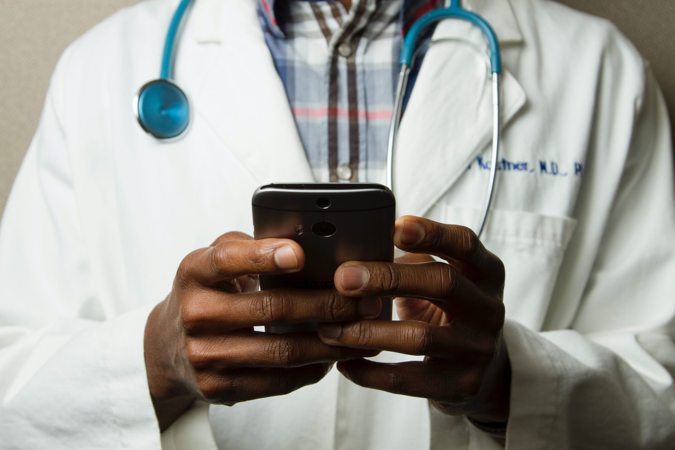 A doctor holds a smartphone is his hands