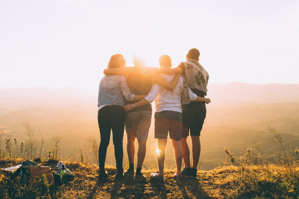Four friends holding each other stands on the mountain
