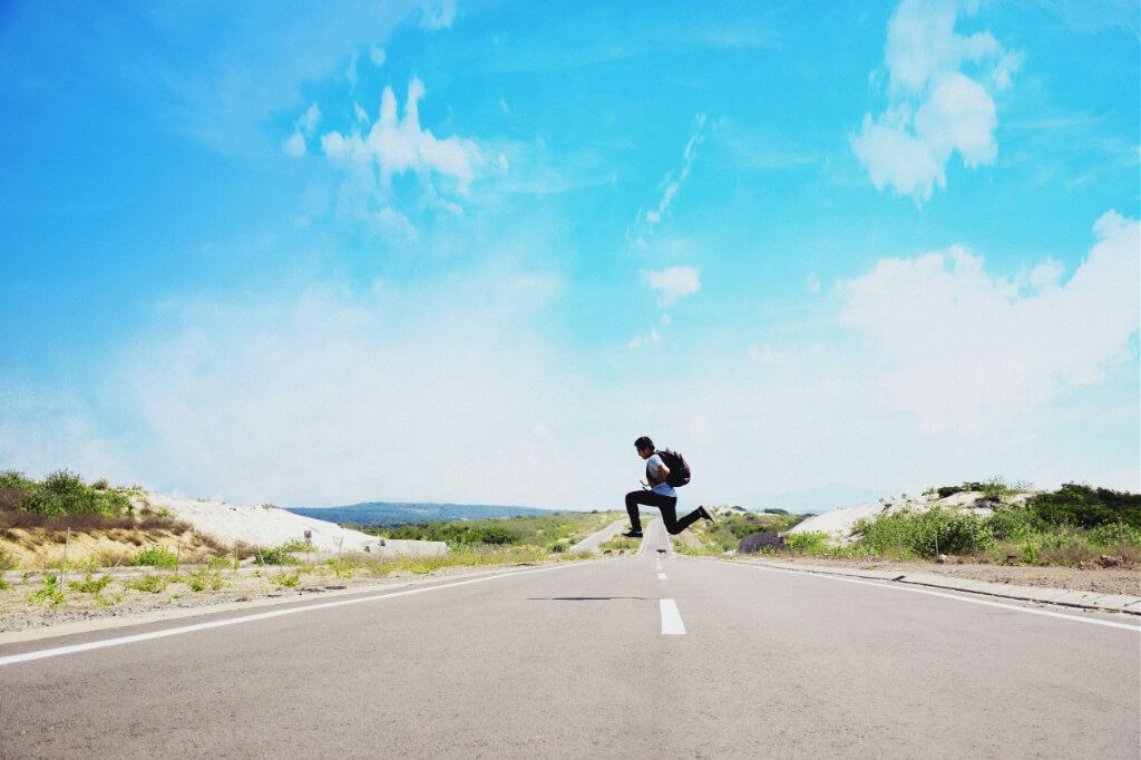 A man jumps while crossing a road