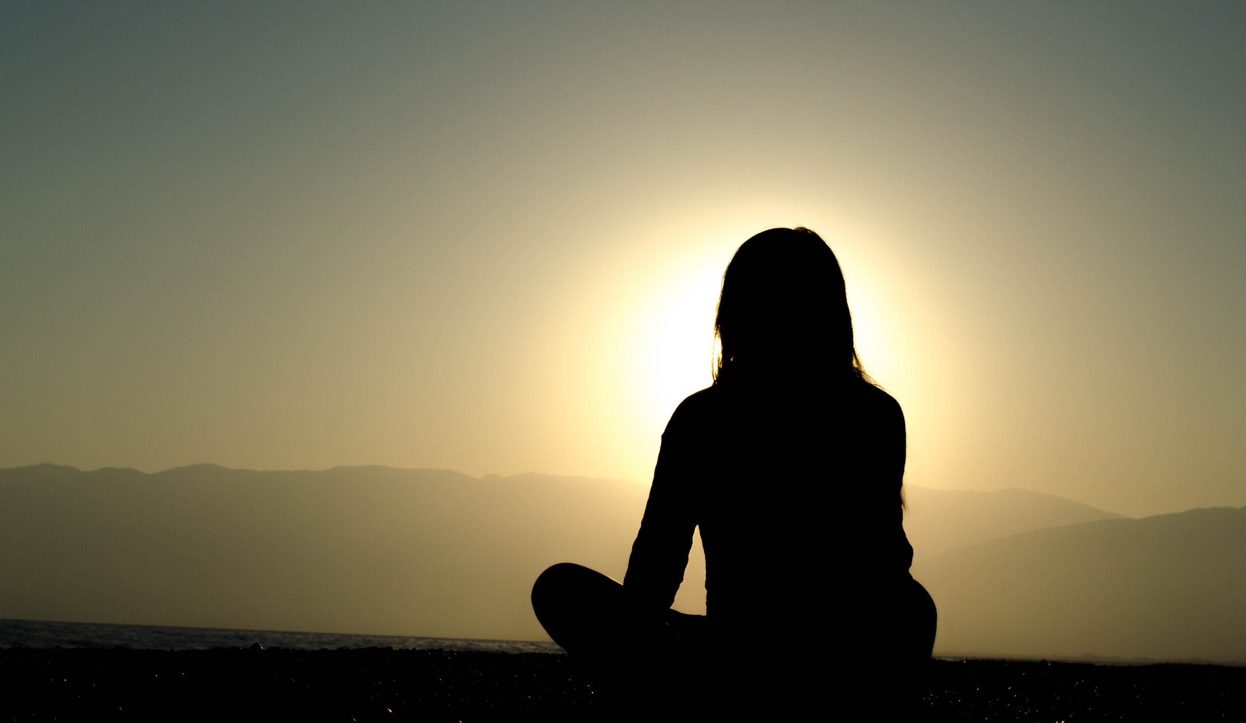 A woman meditating at outdoor facing the sun